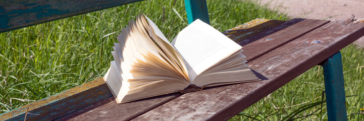 Open book on a park bench on windy day