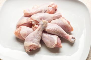 Raw chicken legs on white plate