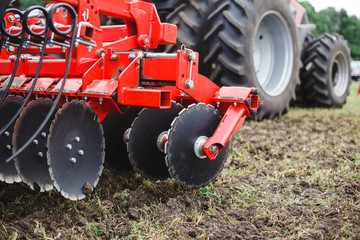 Plow modern tech red tractor close up on an agricultural field Mechanism