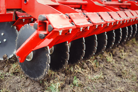 Plow modern tech red tractor close up on an agricultural field