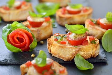 Überbackene Brötchen mit Tomaten, Mozzarella, Olivenöl und Basilikum, mit grünem Pfeffer pikant gewürzt - Hot starters: Crispy baked crostini with tomato, mozzarella, olive oil, garlic and basil 