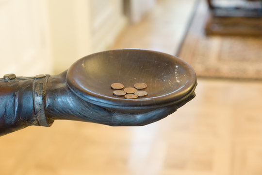 statue hand with coins