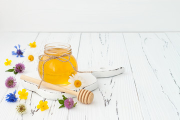 Honey and wild flowers on rustic old wooden background