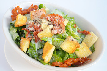 Close up image of delicious ceasar salad in white plate against white background