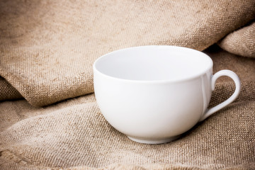 Empty white coffee cup on linen fabric.