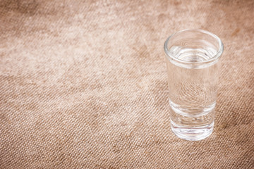 Vodka glasses on retro linen fabric texture. 