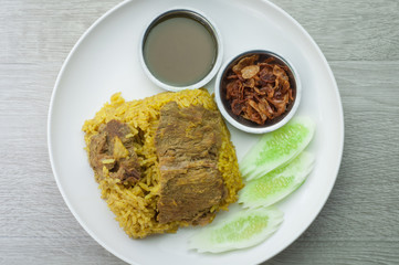 Beef Biryani white plate on a wooden floor.