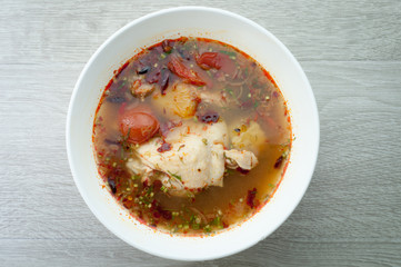 Chicken soup in a white bowl on a wooden floor.