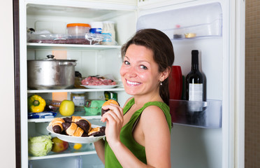 Woman eating cake from fridge