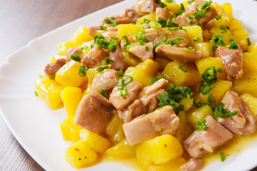 stewed chicken meat with potatoes in a plate on wooden table