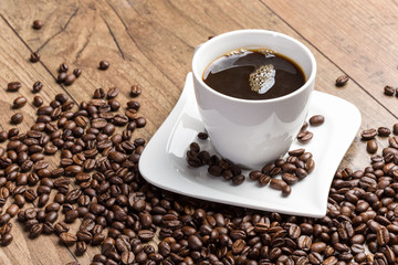 Tasse schwarzer Kaffee und Kaffeebohnen auf Holz