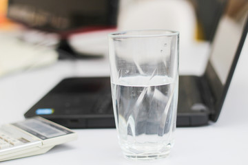 Calculator, laptop and cup of water in a workplace