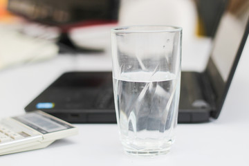 Calculator, laptop and cup of water in a workplace