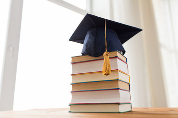 close up of books and mortarboard on wooden table