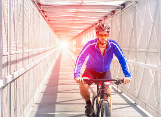    Sport bike man riding inside urban  metal bridge tunnel with sun halo light - Concept of active healthy  green lifestyle outdoor -                                   