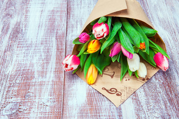 the bouquet of tulips is wrapped in a paper isolated on a wood b