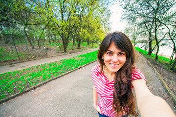 Naklejka premium Portrait of a smiling young girl making selfie photo in park