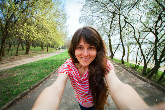 Portrait of a smiling young girl making selfie photo in park