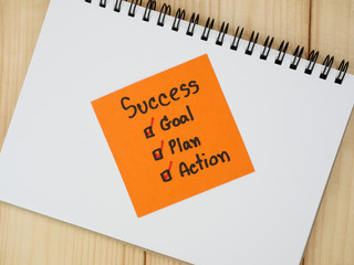 Handwriting word Success, Goal, Plan, Action on blank notebook with wood background (Business concept)
