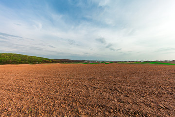 plowed field and cloudy sky in sunset