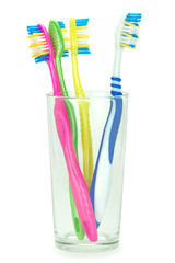 Четыре зубные щетки в стеклянном стакане на изолированном белом фоне