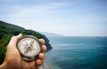 Compass in the hand on the nature background.