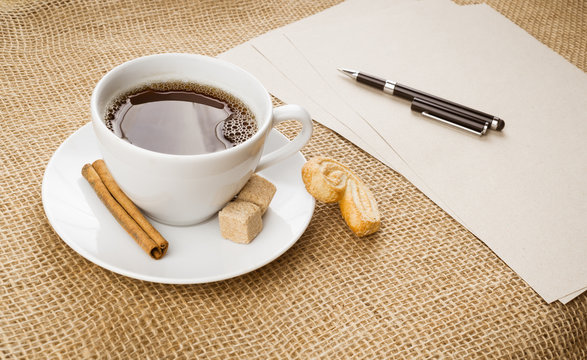 Cup of coffee, cookie, pen and paper on sackcloth background