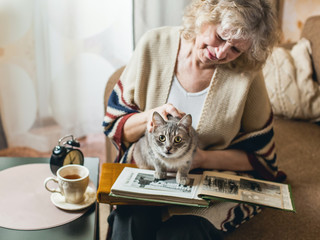 an elderly woman watching photo album with a cat on his lap