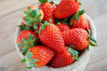 strawberries in small sack on wooden table background