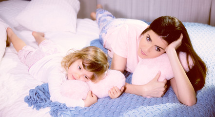Fototapeta na wymiar Romantic atmosphere mother and daughter hugging pink soft hearts in bed