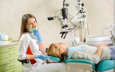 Portrait of cute female dentist checking patient teeth at the dentist clinic, dentist smiling and looking at the camera. Dental care and treatment. Successful treatment