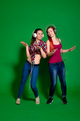 Two young women having fun, listening to music with headphones