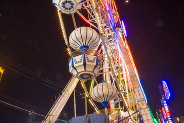 Ferris wheel in motion at amusement park at night