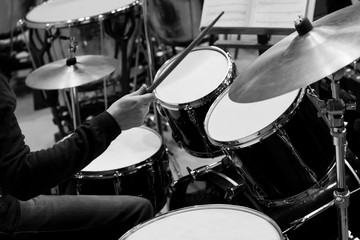 Fototapeta na wymiar Hands of a man playing a drum kit in black and white 