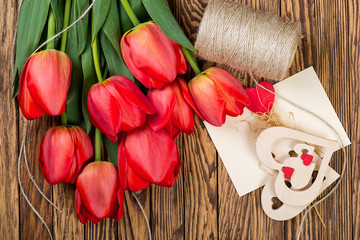 Tulips bouquet and decor with coarse thread on a wooden background.