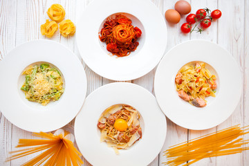 White plates with different Italian pastes decorated by ingredie