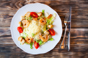 Fresh caesar salad on white bowl with parmesan cheese and shrimp