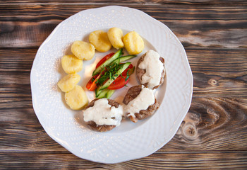 Chicken cutlets and potatoes with vegetables on a wooden backgro