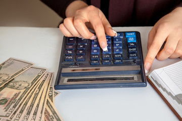female accountant considers dollars on a calculator in the workp