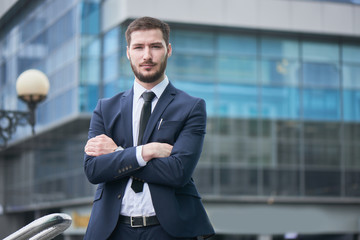 Portrait of young man in suit on the background of the building with a glass facade