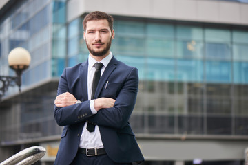 Portrait of young man in suit on the background of the building with a glass facade