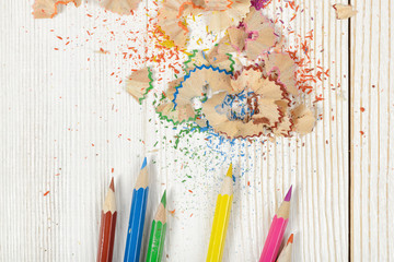 Flat lay of different colored pencils and shavings on table