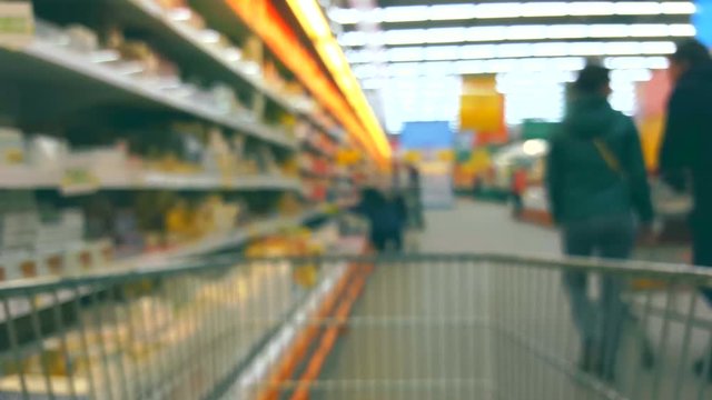 Defocused blurred background supermarket interior with buyers with trolley