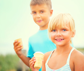 Two happy kids eating ice cream outdoors