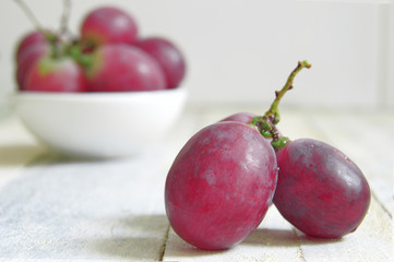 Some grapes on a white wooden table of a rustic kitchen. Empty copy space for editor's text.