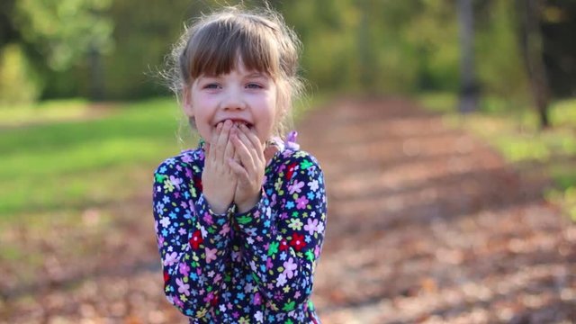 Beautiful cute little girl laughs in sunny autumn park