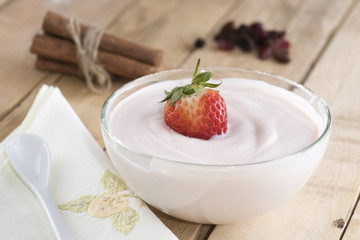 Closeup of delicious strawberry yogurt on wooden table.