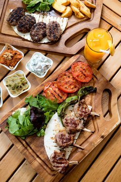 Delicious grilled marinated lamb chops and roasted vegetables from a summer BBQ on a wooden chopping board in a country kitchen