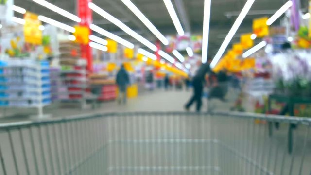 Defocused blurred background supermarket interior with buyers with trolley