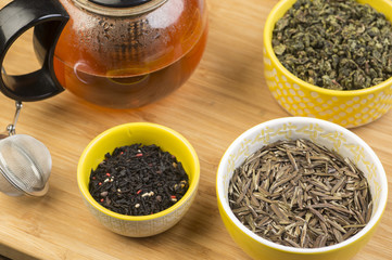Array of teas, black, oolong & white, in ceramic bowls with tea press pot & strainer in the...